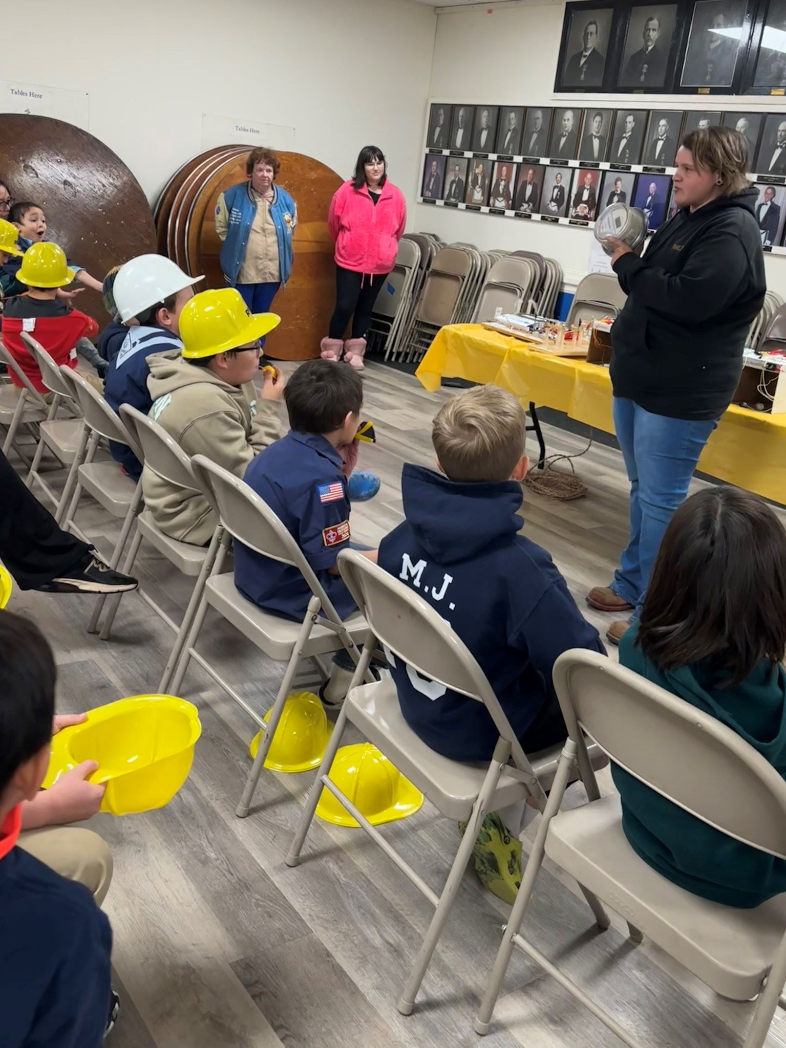 A metering employee holds up a sample meter in front of rows of cub scouts.